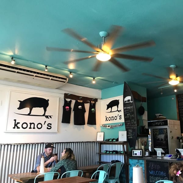 Inside Kono's restaurant with a bright blue ceiling, two people at a table, and branded decor.