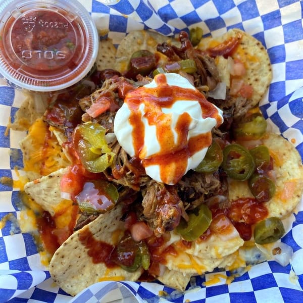 Kono's Hawaiian pulled pork nachos with cheese, jalapeños, sour cream, and salsa in a checkered basket.