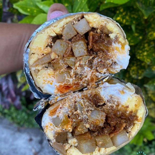 A Kono's breakfast burrito, cut in half, revealing eggs, potatoes, and meat.