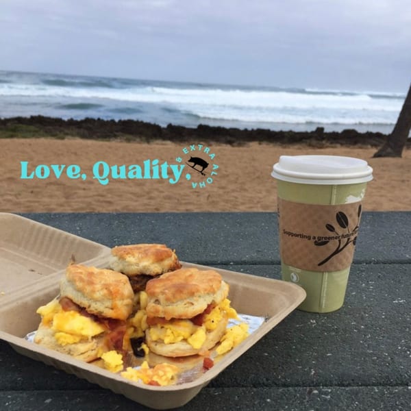 Kono's breakfast biscuits with scrambled eggs and coffee cup on a table overlooking a beach.
